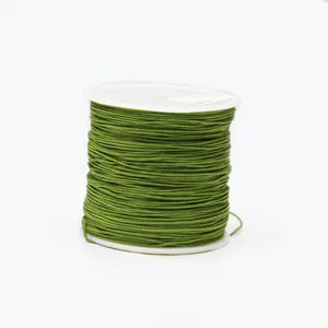 Macro detail of dark green 0.8mm cord neatly wound on a white spool for jewelry making