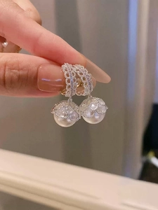 Detailed close-up of a silver earring featuring intricate lace zircon and a large pearl