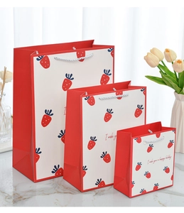 Detailed comparison of three sizes of strawberry print gift bags with woven handles
