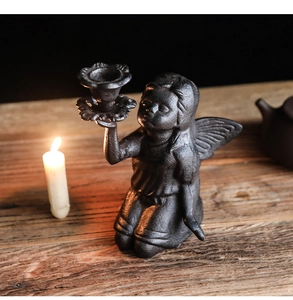 Detail of vintage cast iron kneeling angel candle holder with rustic metal texture