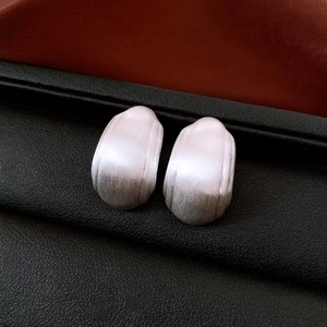 Gros plan de boucles d'oreilles carrées en métal argenté brossé sur cuir noir