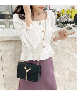 Retro black leather crossbody bag with gold deer head detail and chain strap on model