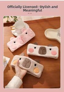 Gros plan de bandeaux capybara en peluche rose, blanc et marron sur une table en bois
