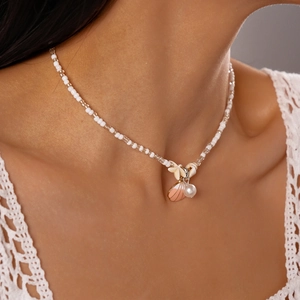 Detail of beach style necklace with pink scallop shell, starfish and white pearls