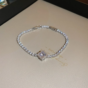 Detail of silver clover tennis bracelet with cubic zirconia on textured background