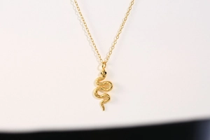 Detailed view of the gold snake pendant showing textured scales and black eyes