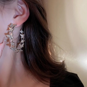 Close-up of model wearing silver hoop earrings with rhinestone butterfly accents