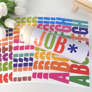 Detail of 2.5 inch waterproof alphabet stickers applied on a modern white insulated tumbler