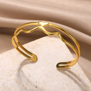 Close-up of golden hollow heart bangle with woven texture on elegant satin background