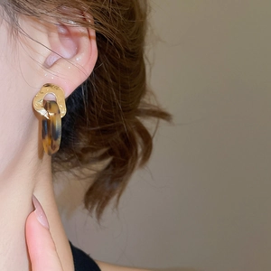 Close-up of geometric acetate tortoise shell earrings with hammered gold rings on model