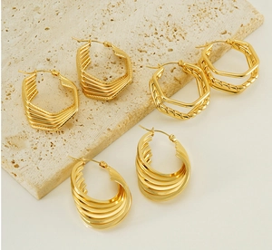 Macro detail of gold geometric earrings with layered hexagonal and oval metal designs