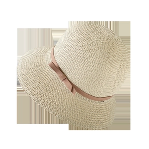 Detail of beige straw hat featuring fine woven texture and decorative pink-brown ribbon bow
