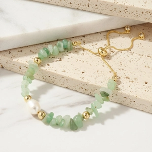 Green crystal stone and freshwater pearl elastic bracelet with gold beads on marble