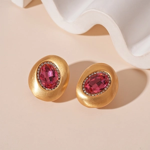 Details von Vintage-Ohrsteckern in Mattgold mit magentafarbenem Edelstein und Kristallen