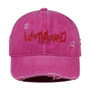 Close-up of distressed pink cotton baseball cap featuring red gothic embroidery text