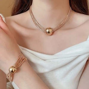 Detail of rose gold multi-layer chain necklace and bracelet with metal ball pendants
