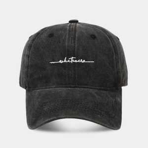 Close-up of white 'whatever' embroidery on a vintage charcoal washed cotton baseball cap