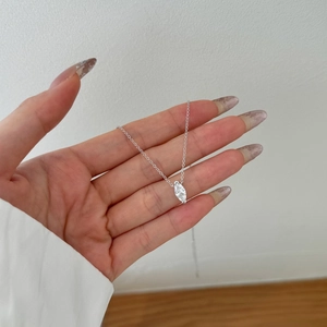 Detail shot of marquise-cut zircon necklace pendant held by hand in soft light