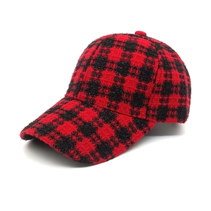 Dettaglio del tessuto in tweed a quadri rossi e neri su un cappello invernale elegante