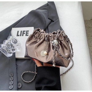 Close-up of pleated metallic cloud bag with drawstring and elegant pearl pendant