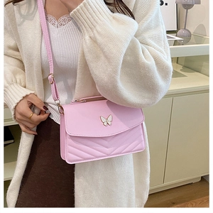 Detailed view of pink crossbody bag with metal butterfly and V-shaped quilted design