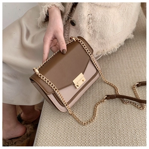 Detail of vintage crossbody bag with gold chain strap and two-tone leather texture
