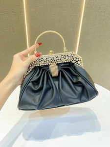 Detail of elegant black pleated evening clutch with crystal-encrusted gold metal handle