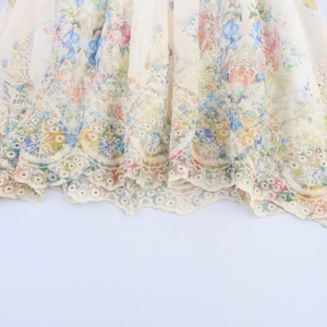 Détail de l'ourlet brodé de fleurs sur robe courte à manches bouffantes blanc cassé