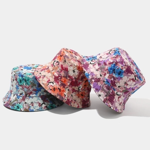 Close-up of three reversible cotton bucket hats with colorful floral patterns and stitched brims