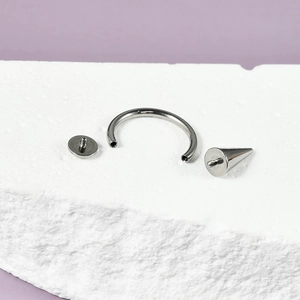 G23 titanium horseshoe ring with cone spike and flat disc on marble stone base
