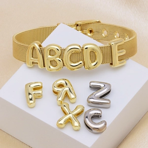 Macro di un bracciale a maglia dorata regolabile con ciondoli a lettere scorrevoli