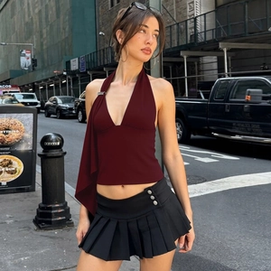 Detail of dark red halter top with metal rings and black pleated skirt details