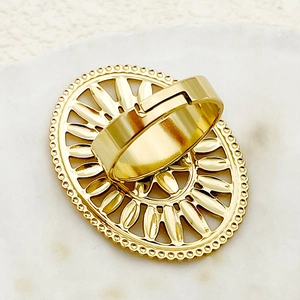 Detailed close-up of golden adjustable oval ring with hollow floral pattern and beaded edge
