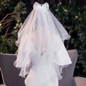 Short two-layer white bridal veil with sheer bow and sparkling rhinestones for weddings