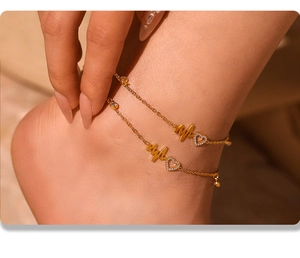 Detail of gold double-layered anklet with heartbeat wave and zircon heart charms