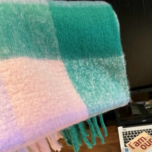 Macro shot of colorful rainbow plaid scarf texture with soft tassels and green pink tones
