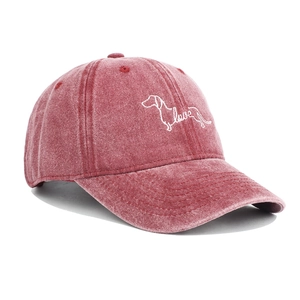 Detail of dachshund embroidery and white love script on washed red cotton baseball cap