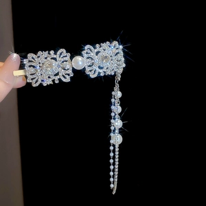 Macro view of silver rhinestone hair clip featuring baroque cutouts and pearl tassels