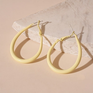 Close-up of matte cream yellow teardrop hoop earrings on elegant marble display