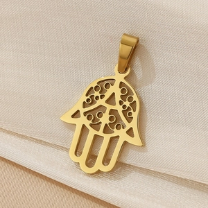 Macro detail of 18K gold plated Hamsa Hand pendant on champagne silk background
