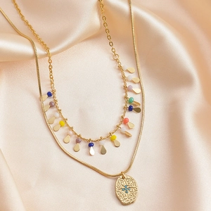 Detail of double-layer gold necklace with blue stone pendant and colorful beads on silk
