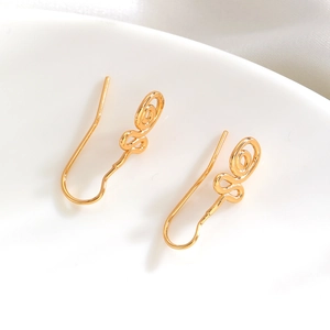 Macro shot of minimalist gold plated spiral wire hoop earrings on white porcelain