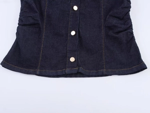 Dettaglio giacca di jeans blu scuro con bottoni dorati, cuciture arancioni e arricciatura