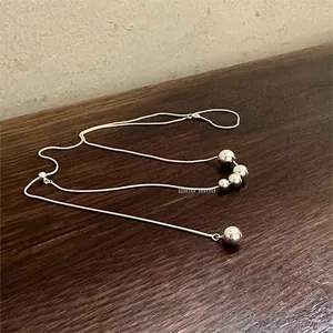 Detail of silver beaded necklace with four polished spheres on a wooden surface