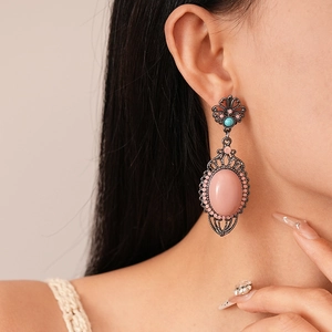 Detailed view of vintage bronze hollow earrings with pink floral resin and blue stones
