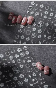 Detailed view of white floral nail stickers with embossed textures on pink nails
