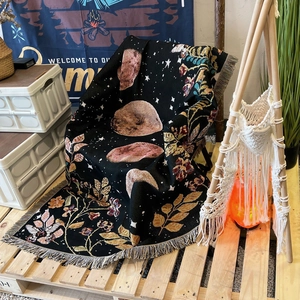 Bohemian moon phase camping blanket with floral patterns and tassels on a chair