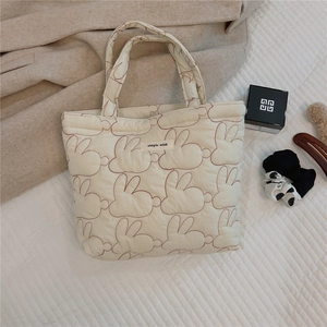 Close-up of cream quilted tote bag featuring rabbit embroidery and soft fabric texture