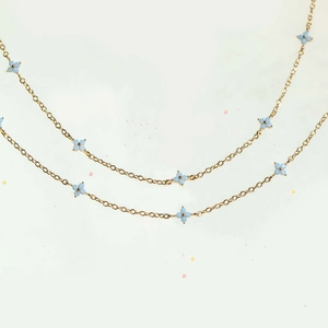 Minimalist golden chain anklet with blue flower pendants for a fresh summer beach look