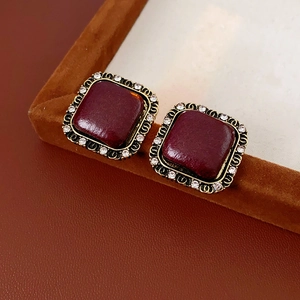 Dettaglio macro di orecchini retrò quadrati con smalto bordeaux e cornice dorata con cristalli